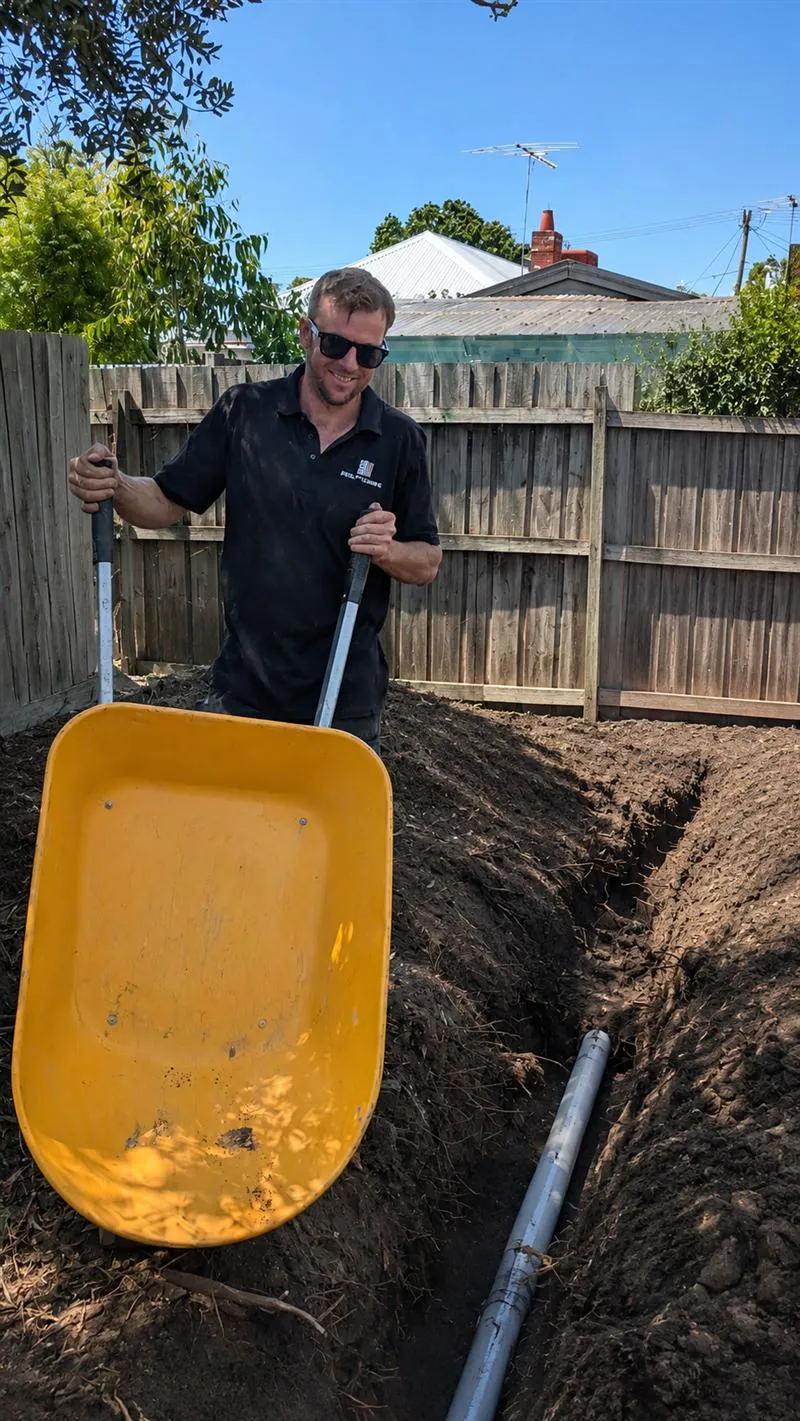Taylor backfilling a trench with a new stormwater line in a backyard