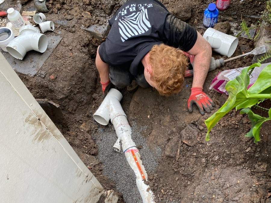 A Zebra plumber laying the new sewer-grade PVC junction on the crushed rock bed at the Kensington renewal