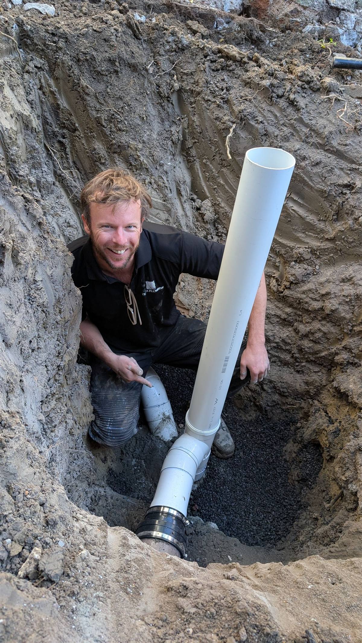 Taylor from Zebra Plumbing connecting the new PVC sewer riser on a renewal, deep in the excavation