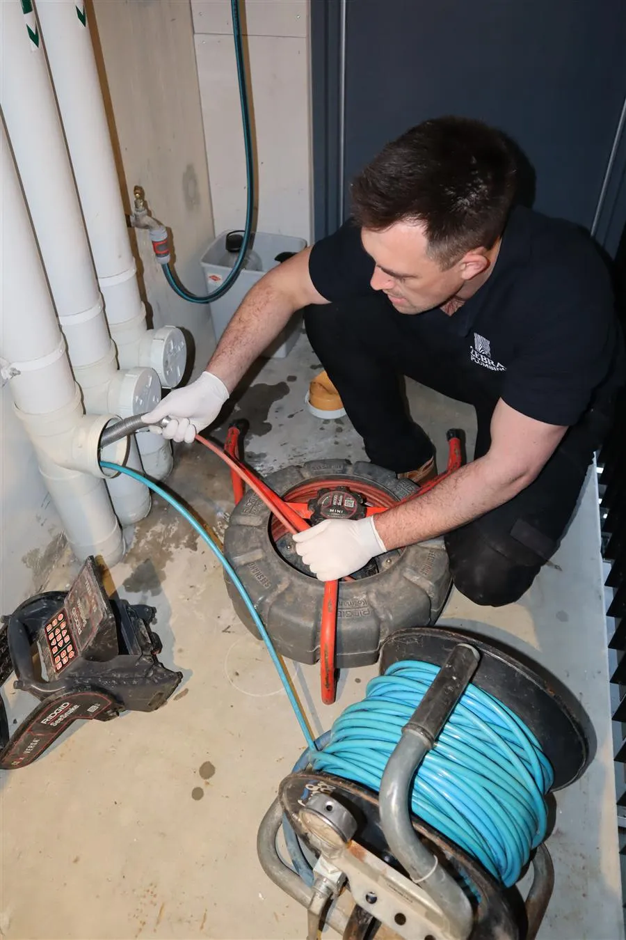Byron feeding the CCTV camera reel and jetter hose into the pipework