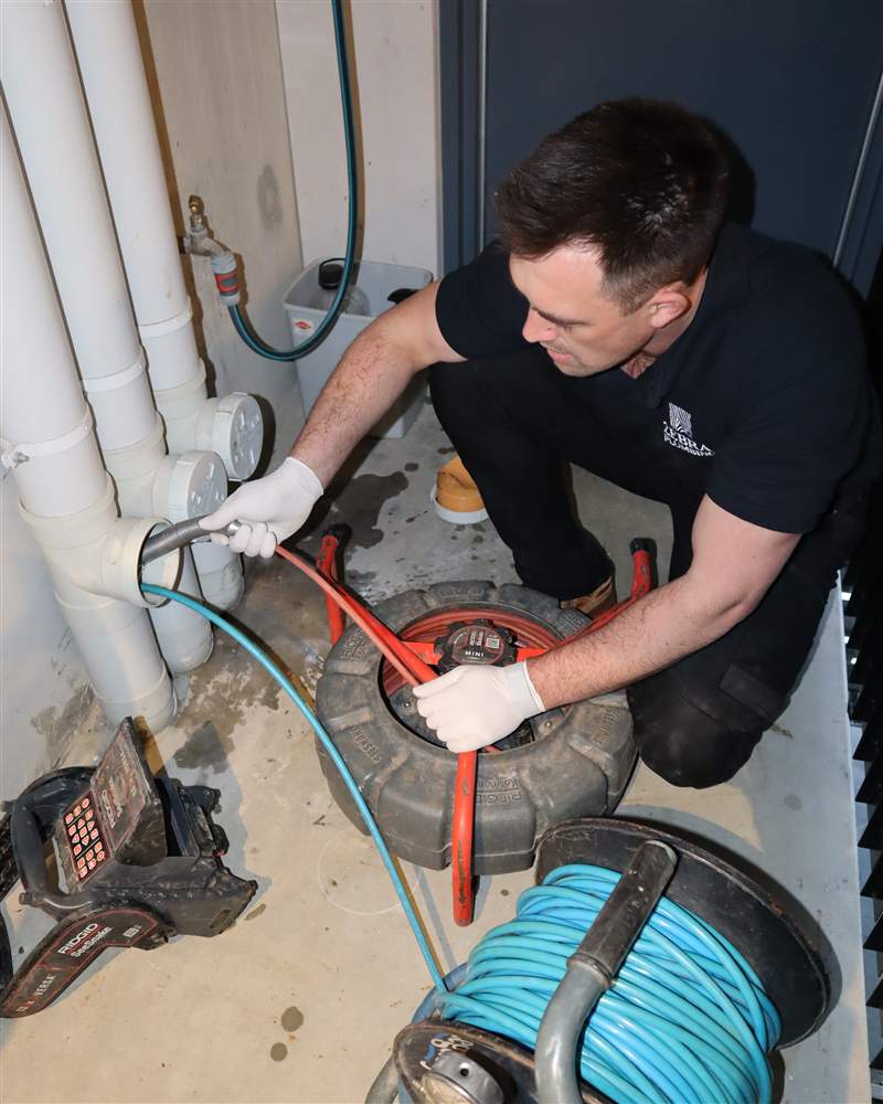 Byron from Zebra Plumbing feeding the CCTV drain camera into an inspection opening