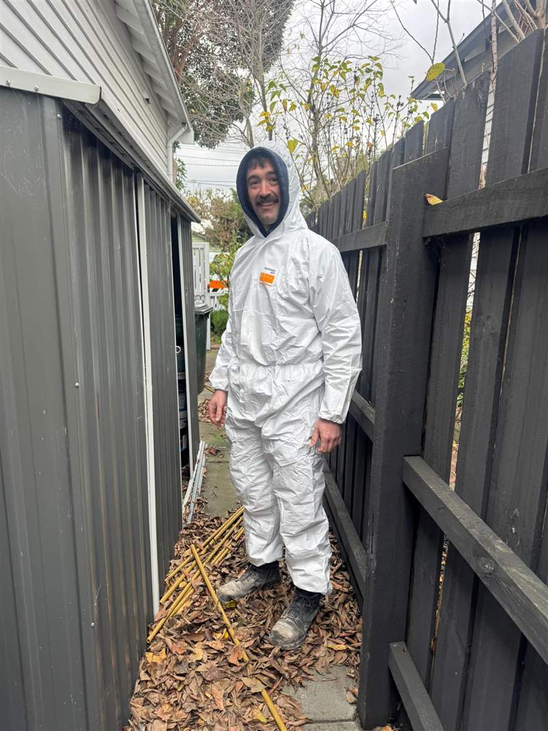 A Zebra plumber in clean white coveralls before crawling under a house